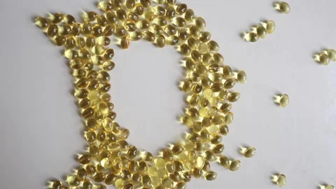 Vitamin D softgel capsules forming a large letter D on white background Видео 344043900