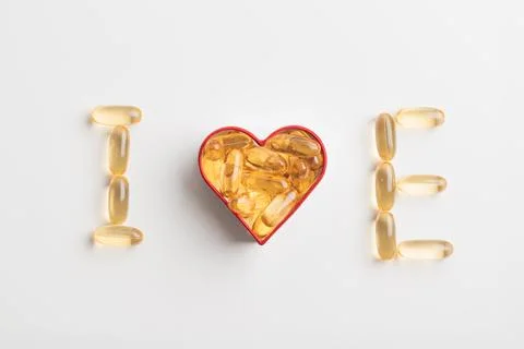 Vitamin E. The letter E and heart from yellow pills on a white background. .. 스톡 사진