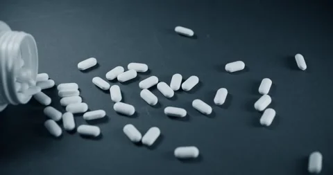 Vitamin pills and bottles on a dark background slowly fly out of the jar Stock Footage 302901853