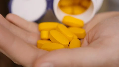 Vitamins And Supplements. Close up Hand Holding Variety of Yellow Pills on Pa Stock Footage 127983031