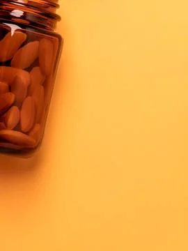 Vitamins in a brown glass jar on a solid yellow orange background Foto stock