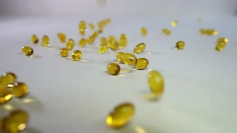 Vitamins D and Diet Tablets omega-3 supplements fall onto a white surface. Stock Footage 168248419