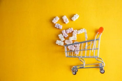 Vitamins in the form of bears on a yellow background with a toy cart Stock Photos