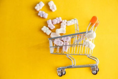 Vitamins in the form of bears on a yellow background with a toy cart Stock Photos