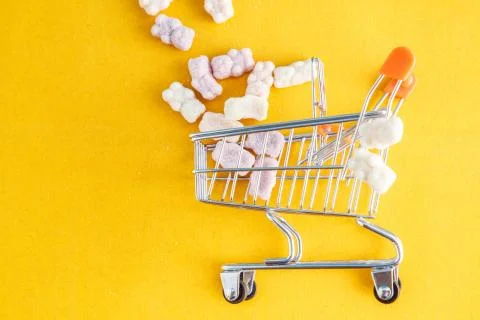 Vitamins in the form of bears on a yellow background with a toy cart Stock Photos