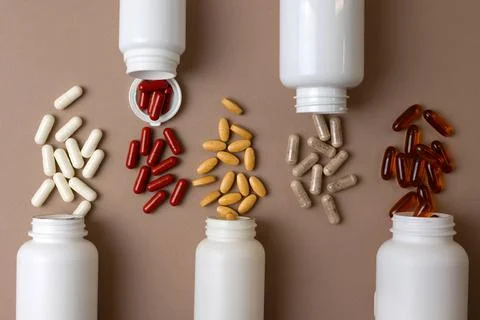 Vitamins On Neutral Background. Assorted Supplement Bottles With Capsules On Foto stock
