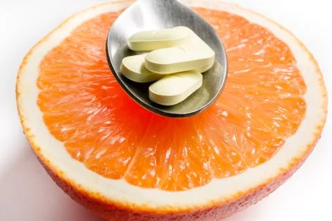 Vitamins in a spoon, lying on a grapefruit. Stock Photos