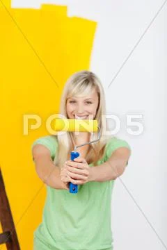 Vivacious woman painting with yellow paint Stock Photos