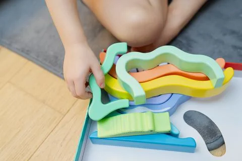 Vivid assortment of learning shapes handled by child seated on soft mat Stock Photos