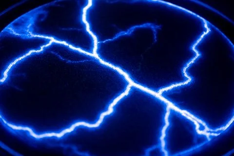 Vivid blue lightning patterns illuminate the dark background, creating a stri Stock Photos