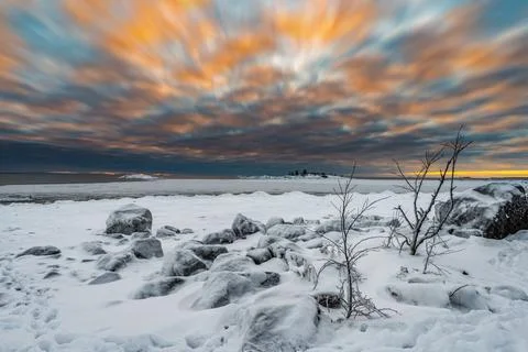 A vivid cloudscape of dramatic evening sky and snow covered half frozen lake  Stock Photos