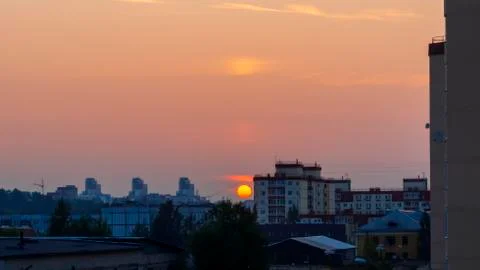 Vivid disk of the sun at sunset on a background of tall buildings of city 스톡 사진