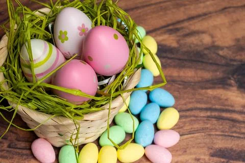 Vivid Easter Display Featuring Overflowing Basket And Treats On Wooden Surface Stock Photos