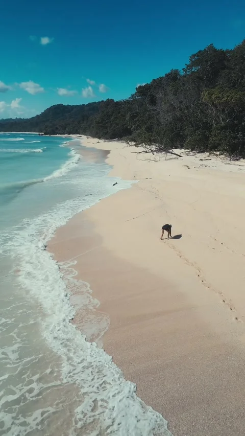 Vivid high view displaying surfer along turquoise coastline with footprints Video stock 336928373