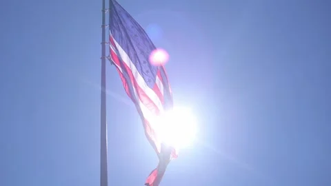 Vivid image showcasing flag waving under intense sunlight glare, Energetic Stock Footage 323575384