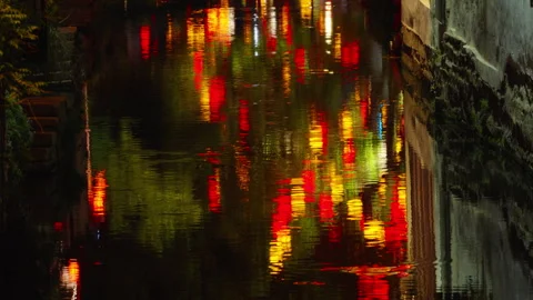 Vivid Lantern Reflections Shimmer on Calm Canal Water by Night in Urban Area Видео 336655594