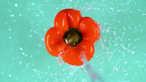 Vivid orange pepper spinning dramatically while fresh water splashes over c.. Stock Footage 327587830
