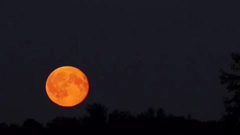A vivid red moon glows in the night sky, partially veiled by swirling hot air. Stock Footage 317107620