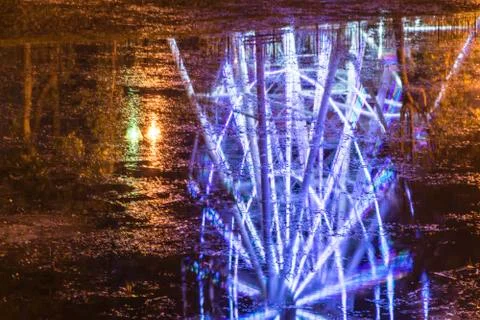 A vivid reflection of a observation wheel in dark river water. Stock Photos