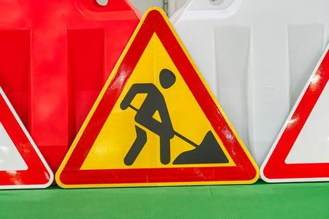 Vivid scene featuring two bright yellow caution signs with man shoveling grap 스톡 사진