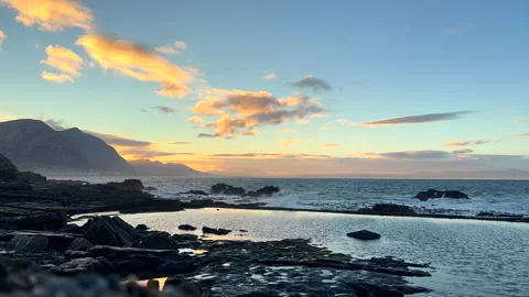 Vivid sunrise clouds fly over ocean viewed over Hermanus marine pool Vídeo Stock 345994793