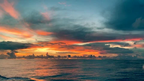 Vivid sunset over a calm ocean with colorful clouds reflecting on the water.. Stock Footage 338280298