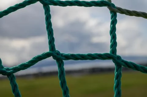 Vivid turquoise netting frames a blurred landscape under an expansive cloud.. Stock Photos
