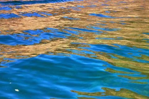 Vivid Water Surface Reflection with Blue and Gold Abstract Patterns 库存照片