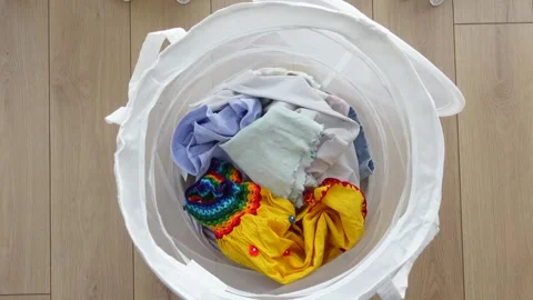 A vividly colored laundry basket filled with a wide variety of different clothes Stock Footage 284596681