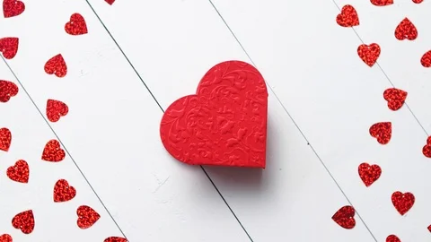 Vlentine's Day composition. Heart shaped sequins placed on white wooden table Stock Footage 101019247