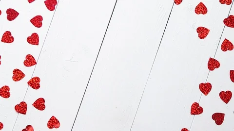 Vlentine's Day composition. Heart shaped sequins placed on white wooden table Stock Footage 101019473