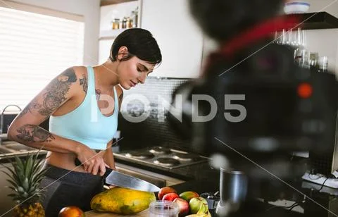 Vlogger in kitchen recording video on camera Stock Photos