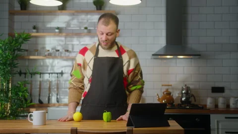 Vlogger man chef in an apron talking into tablet computer, recording video .. Stock Footage 262954098