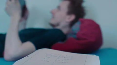 Vocabulary Study Notes with Distracted Student playing video games in Background Video stock 341749662
