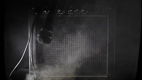 Vocal microphone swinging around the circle in front of guitar amplifier smoke s Stock Footage 204960339