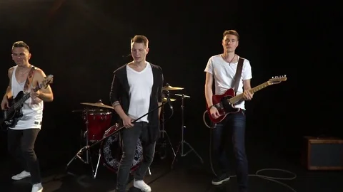 The vocalist and two guitarists are jumping together, slow motion Stock Footage