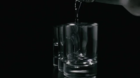 Vodka from a bottle pours into a shot. Slow motion Stock Footage 74619668