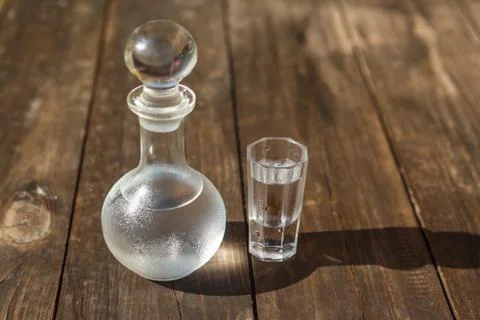 Vodka cold in a decanter and a stack lit by the bright sun Stock Photos