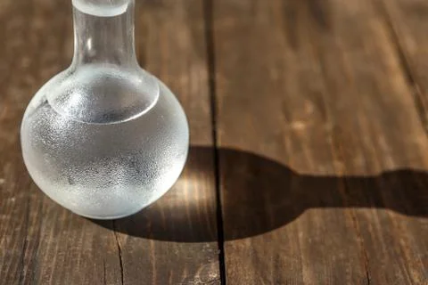Vodka cold in a decanter and a stack lit by the bright sun Stock Photos