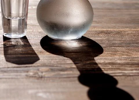 Vodka cold in a decanter and a stack lit by the bright sun Stock Photos
