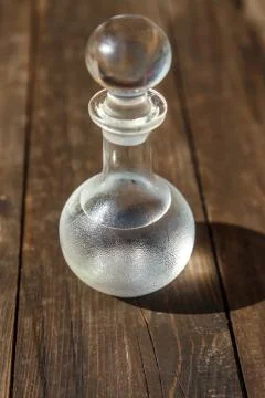 Vodka cold in a decanter and a stack lit by the bright sun Stock Photos