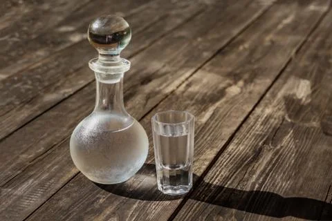 Vodka cold in a decanter and a stack lit by the bright sun Stock Photos