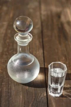 Vodka cold in a decanter and a stack lit by the bright sun Stock Photos