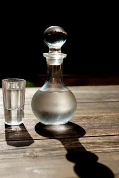 Vodka cold in a decanter and a stack lit by the bright sun Stock Photos