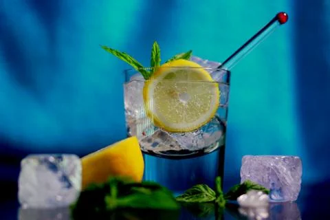 Vodka lemon with ice cubes in blue background. Stock Photos
