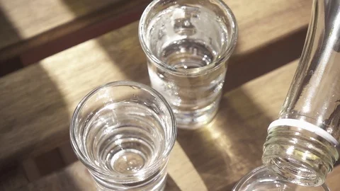 Vodka is poured into one of the glasses on the table slow motion Stock-Footage 88916662