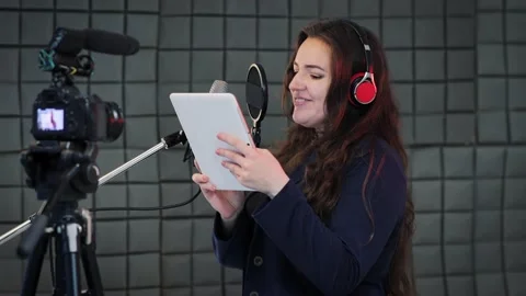 Voice actress reads text from digital tablet and dubbing to the microphone Stock Footage 134205946