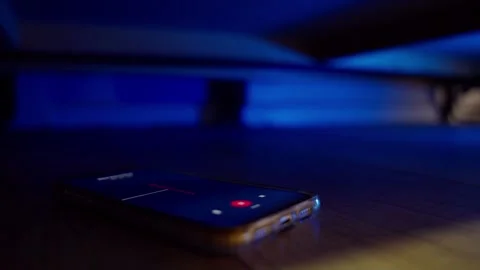 Voice app on phone recording conversation sound while hidden under couch or bed Stock Footage 310200089