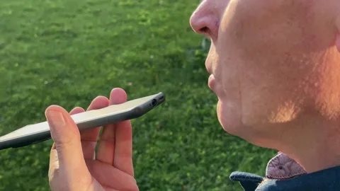 Voice message recording on a mobile device by a man holding his phone close.. Stock Footage 346154558