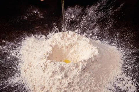 Volcan de harina para preparar masa con huevo sobre base oscura Stock Photos